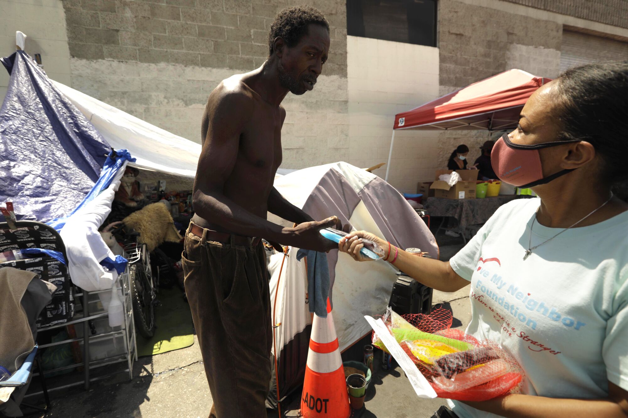 A woman hands a popsicle to a shirtless man