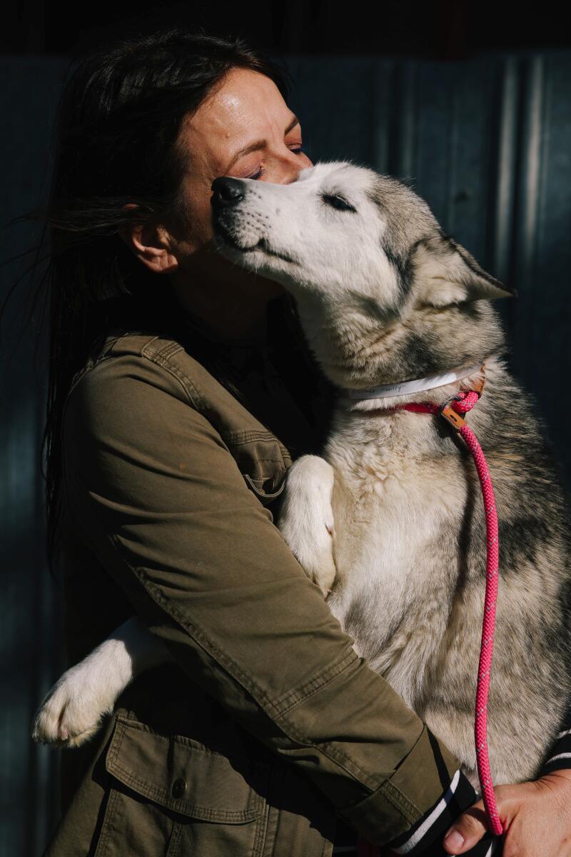 Rita Earl Blackwell hugs a dog with Husky coloring as it snuggles into her face.