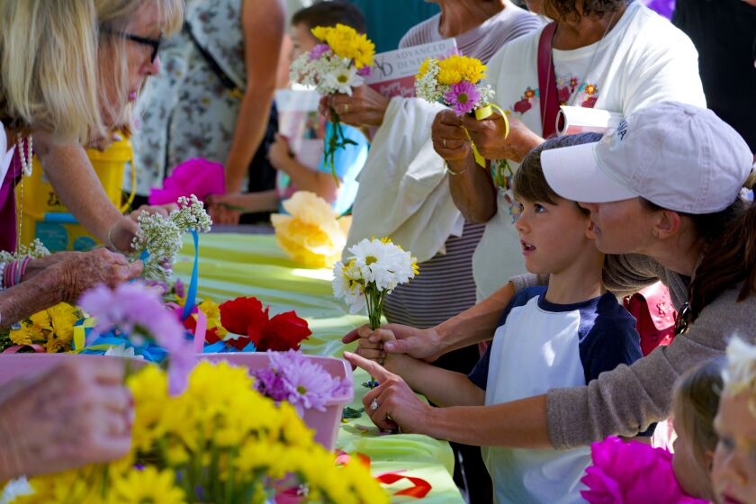 Coronado, CA - April 23: At the 100th Annual Coronado Flower Show held at Spreckels Park on Saturday, April 23, 2022 in Coronado, CA., Jack Durkin with his mother, Brittany Durkin get a little help from Alexis Boering (l) with Bridge and Bay Garden Club with completing his small bouquet of flowers. (Nelvin C. Cepeda / The San Diego Union-Tribune)