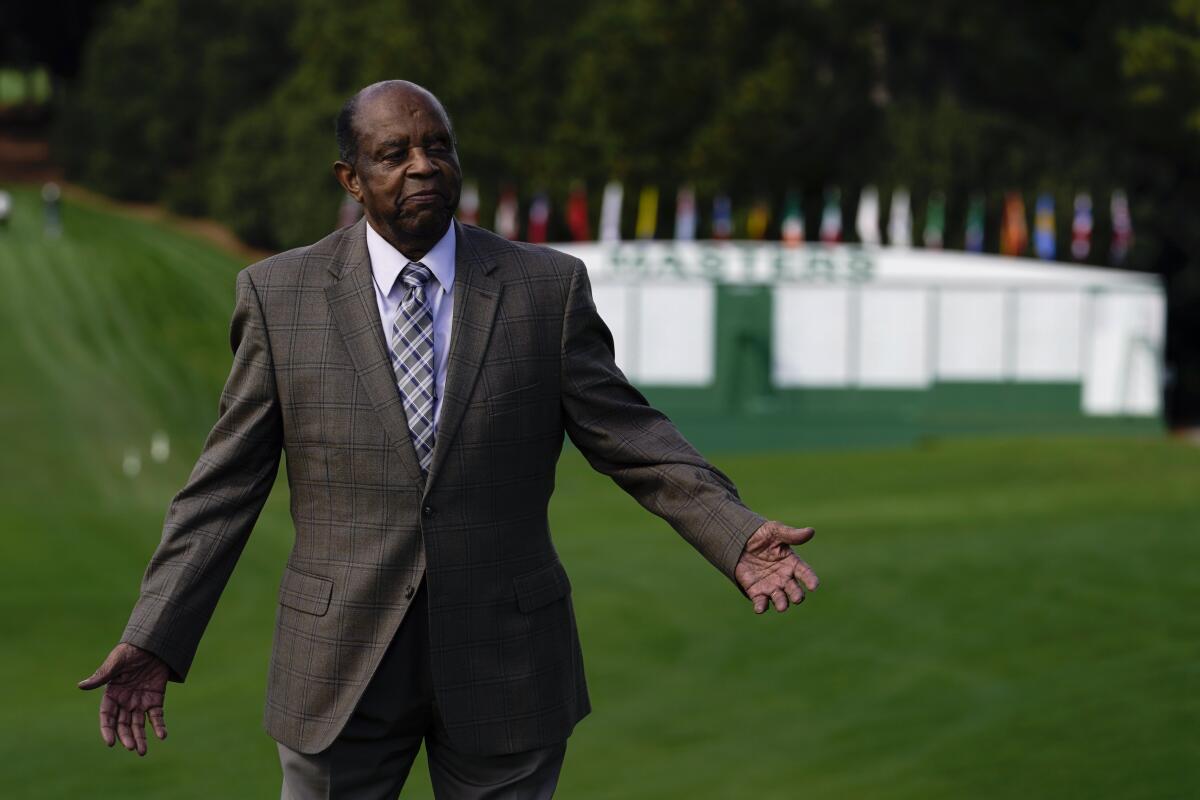 Lee Elder, in suit and tie, is photographed on a golf course.