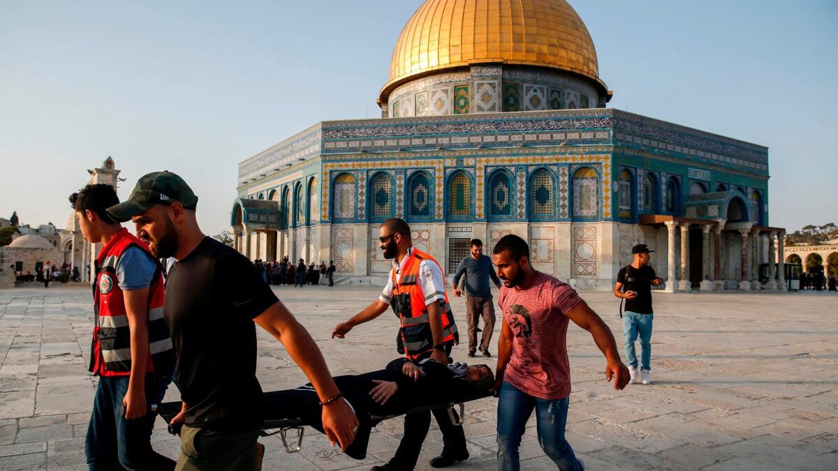 Palestinian paramedics carry an injured woman on a stretcher past the Dome of the Rock after clashes broke out inside the Al Aqsa Mosque compound.