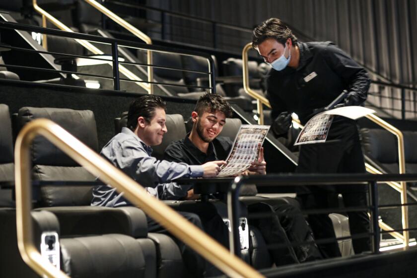 Left, Vassilis Xykis and Sabastian Theodoropoulas order food from Alex Phiakeo before the start of a movie at Theater Box on Wednesday in Downtown San Diego, April 7, 2021.(Photo by Sandy Huffaker for The San Diego Union-Tribune)