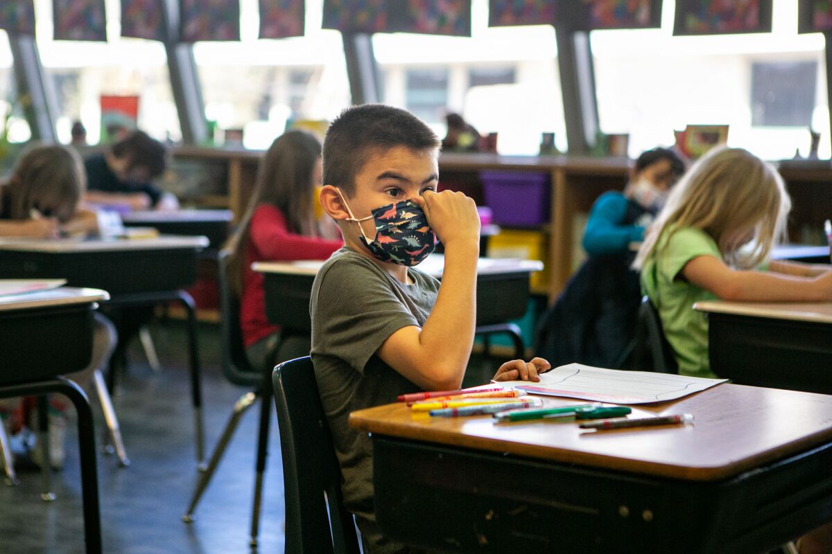  A student adjusts his face mask while in class