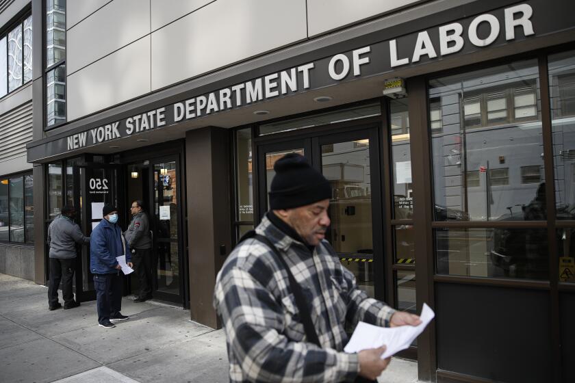 Personal de las oficinas del Departamento del Trabajo en Nueva York impide pasar a personas dentro de los cierres dispuestos por temor al coronavirus, el miércoles 18 de marzo de 2020. (AP Foto/John Minchillo)