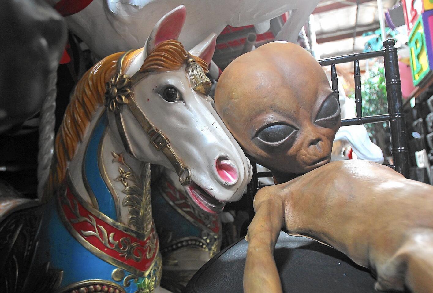 A merry-go-round horse and an alien sit side by side inside the BTB Event Production warehouse in Costa Mesa.
