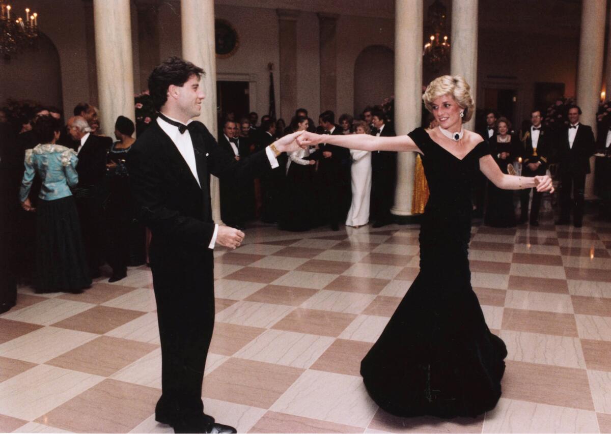  November 1985: Diana wears a couture black gown by Victor Edelstein to a White House dinner and dances with John Travolta.