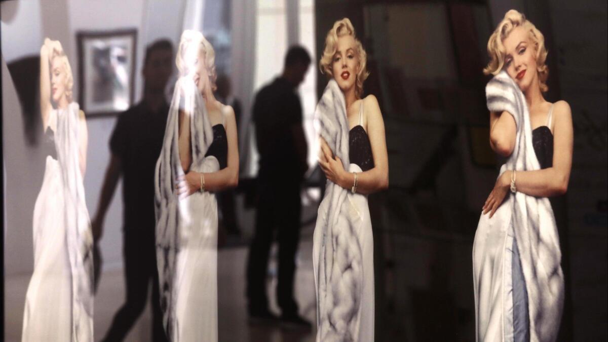 Visitors are reflected in Milton H. Greene photos titled "Marilyn Monroe —Negligee Series c. 1953," part of "Essentially Marilyn: The Exhibit" at the Paley Center for Media in Beverly Hills.