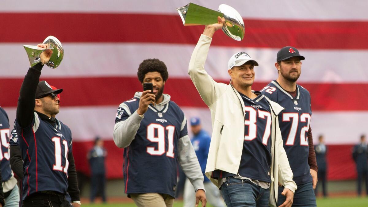 Rob Gronkowski, second right, holds the Lombardi Trophy while walking with New England Patriots teammates (from left) Julian Edleman, Deatrich Wise and Dan Skipper during the Boston Red Sox's home opener on April 9.