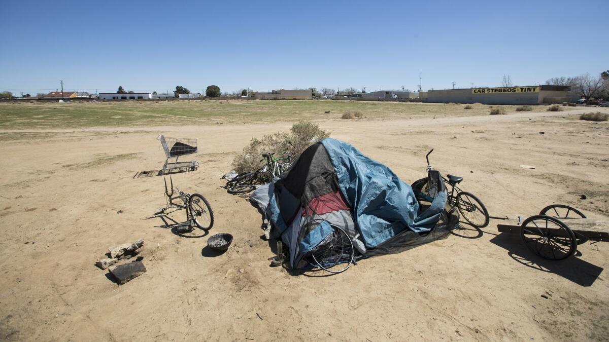 A tent is surrounded by bicycles in various states of disrepair on a vacant lot in Lancaster.