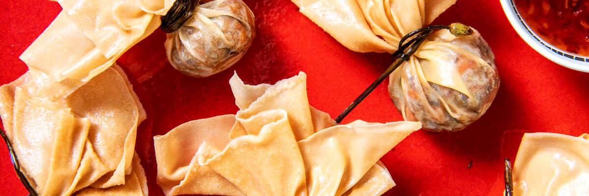 Deep-Fried Golden Bags scattered on a red background with a bowl of Thai Sweet Chile dipping sauce nearby.