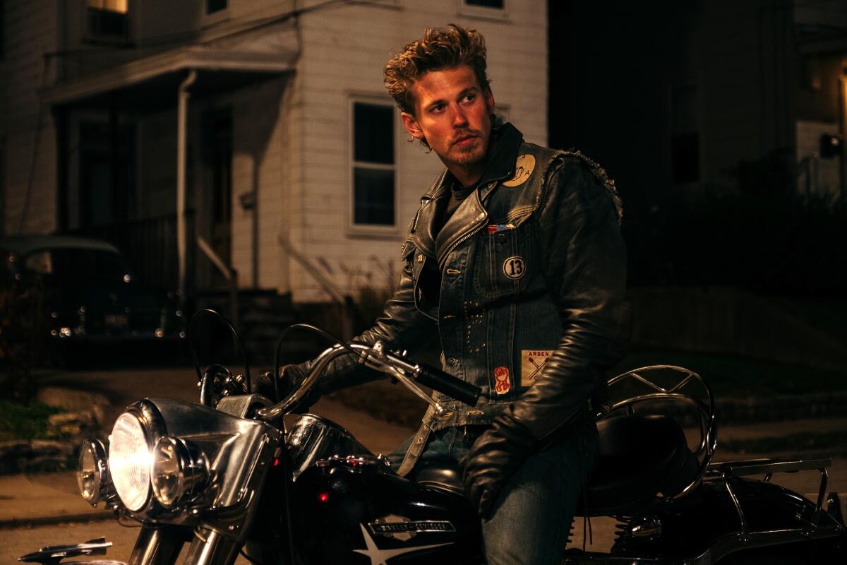A man in leather sits on a motorcycle.