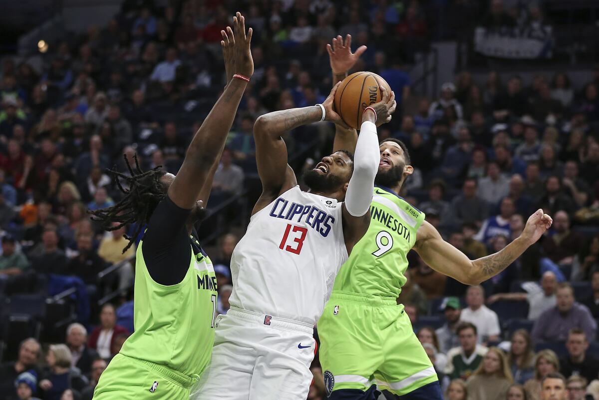 Clippers forward Paul George tries to score despite the double-team defense of Minnesota's Naz Reid, left, and Allen Crabbe (9) during a game Feb. 8, 2020, in Minneapolis.
