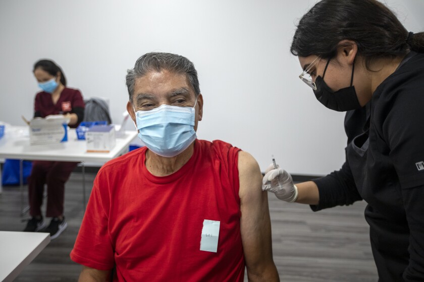 EL MONTE, CA - NOVEMBER 17: Irene Michel, right, gives Jaime Sores, 70, left, a Covid-19 vaccination booster. Through a jointly-operated Community Resource Center, L.A. Care Health Plan and Blue Shield of California Promise Health Plan host a food pantry, pumpkin pie giveaway and COVID-19 vaccine clinic on Wednesday, Nov. 17, 2021 in El Monte, CA. (Francine Orr / Los Angeles Times)