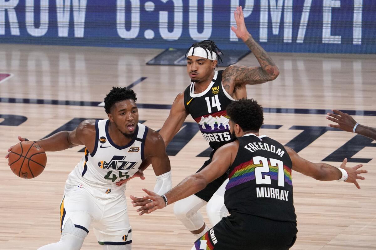 Utah's Donovan Mitchell looks for an opening between Denver's Gary Harris and Jamal Murray.