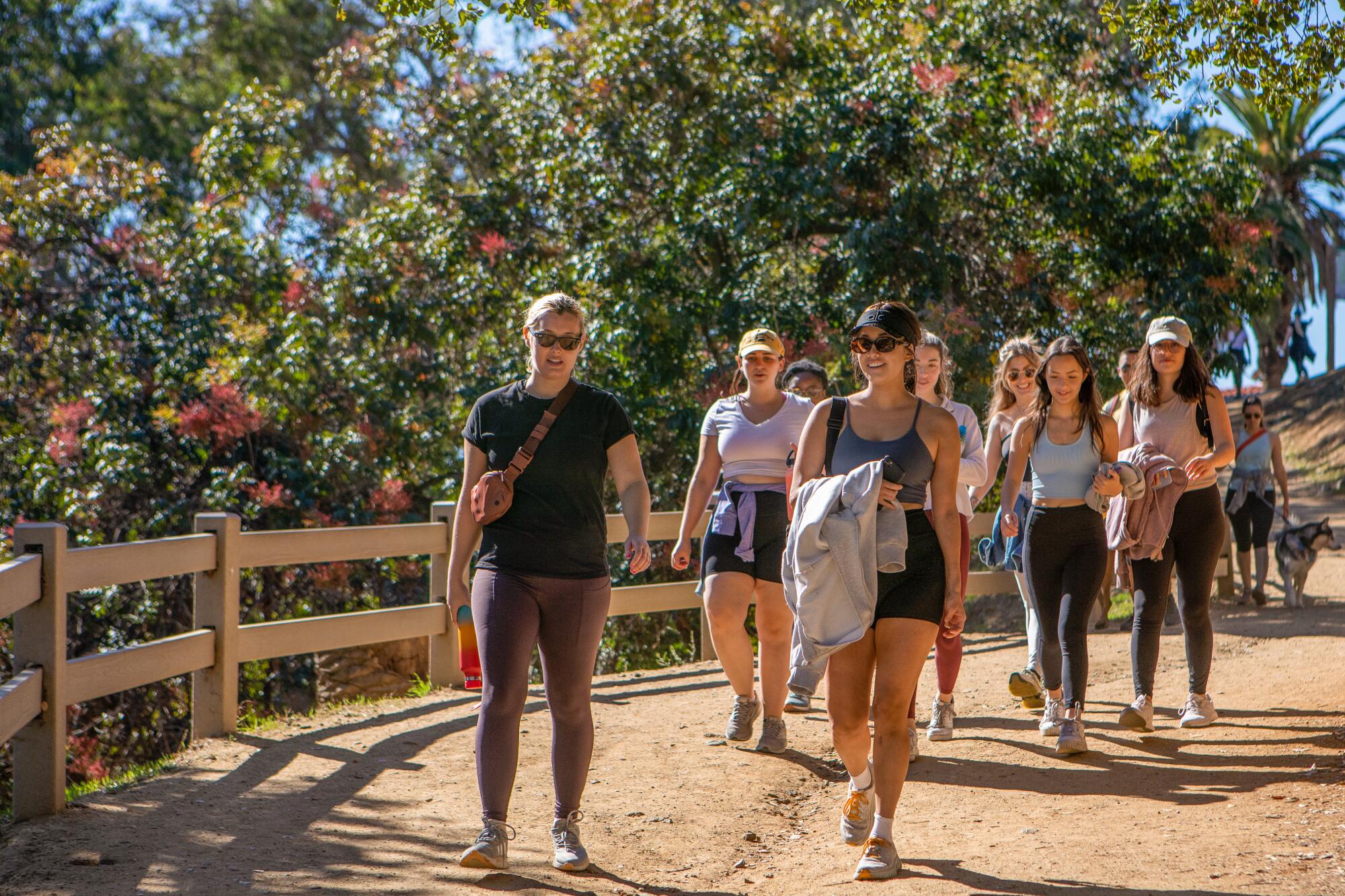 A group of women in athletic gear walking on a dirt path.