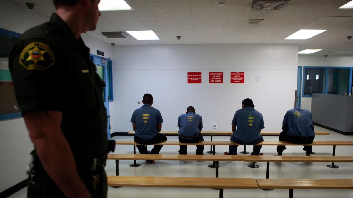 An Orange County sheriff's deputy watches over a group of detained immigrants in the medical area at the Theo Lacy Facility.