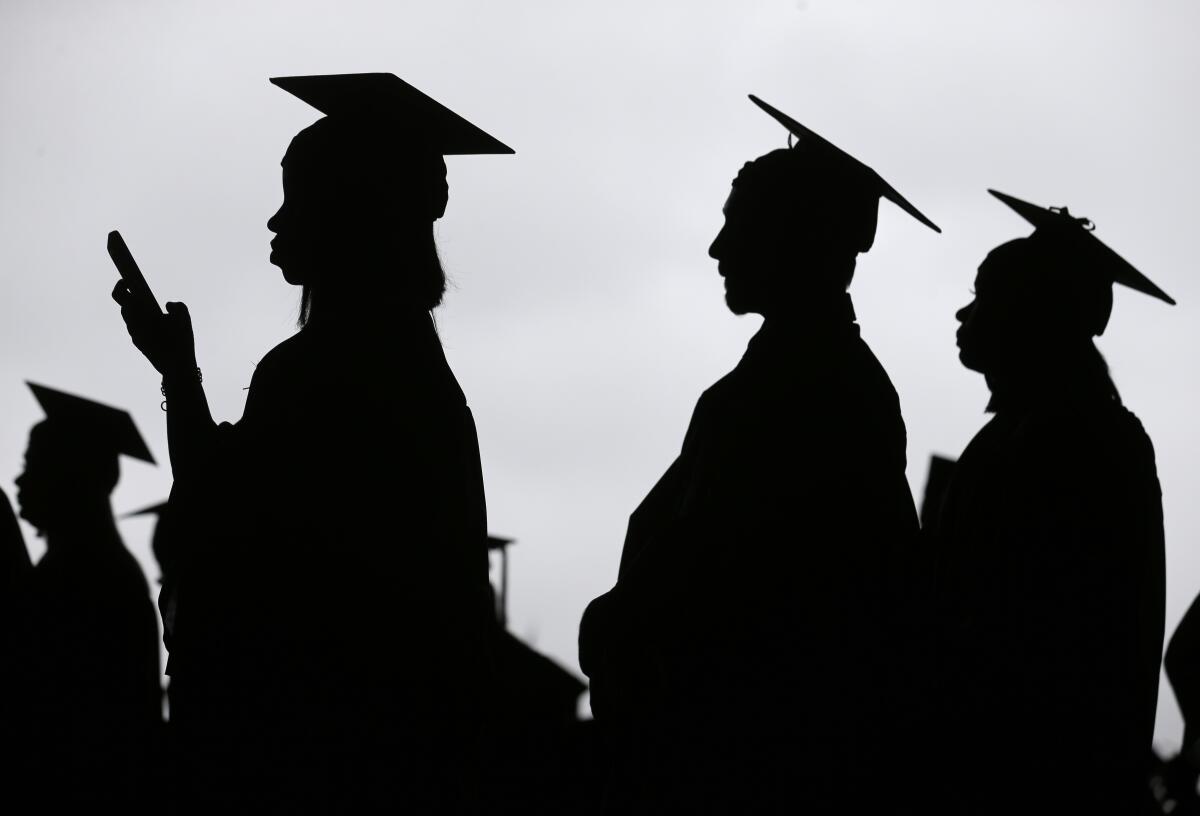 This photo shows silhouettes of students lined up at a college graduation.