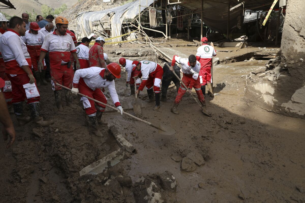Rescue workers clean up mud after flash flooding.