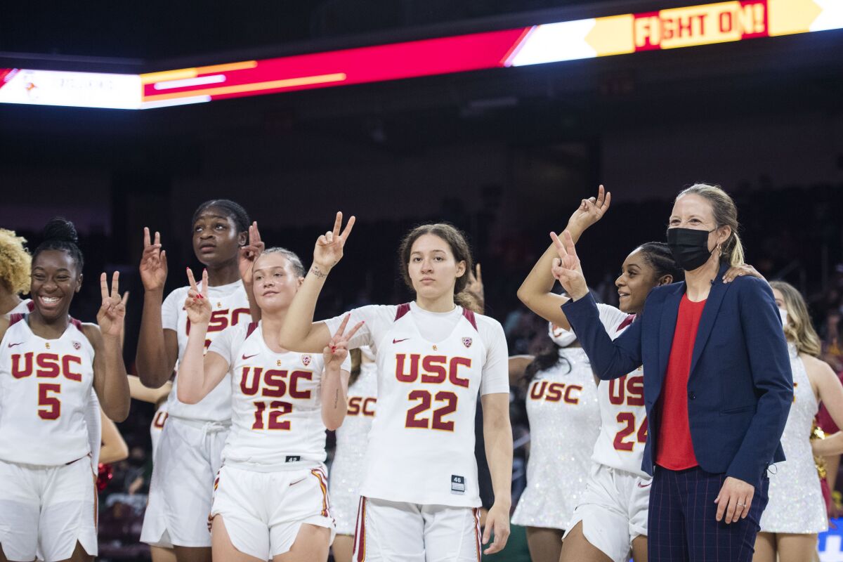 USC head coach Lindsay Gottlieb and the players hold up their fingers in V signs after the team's win over Hawaii.