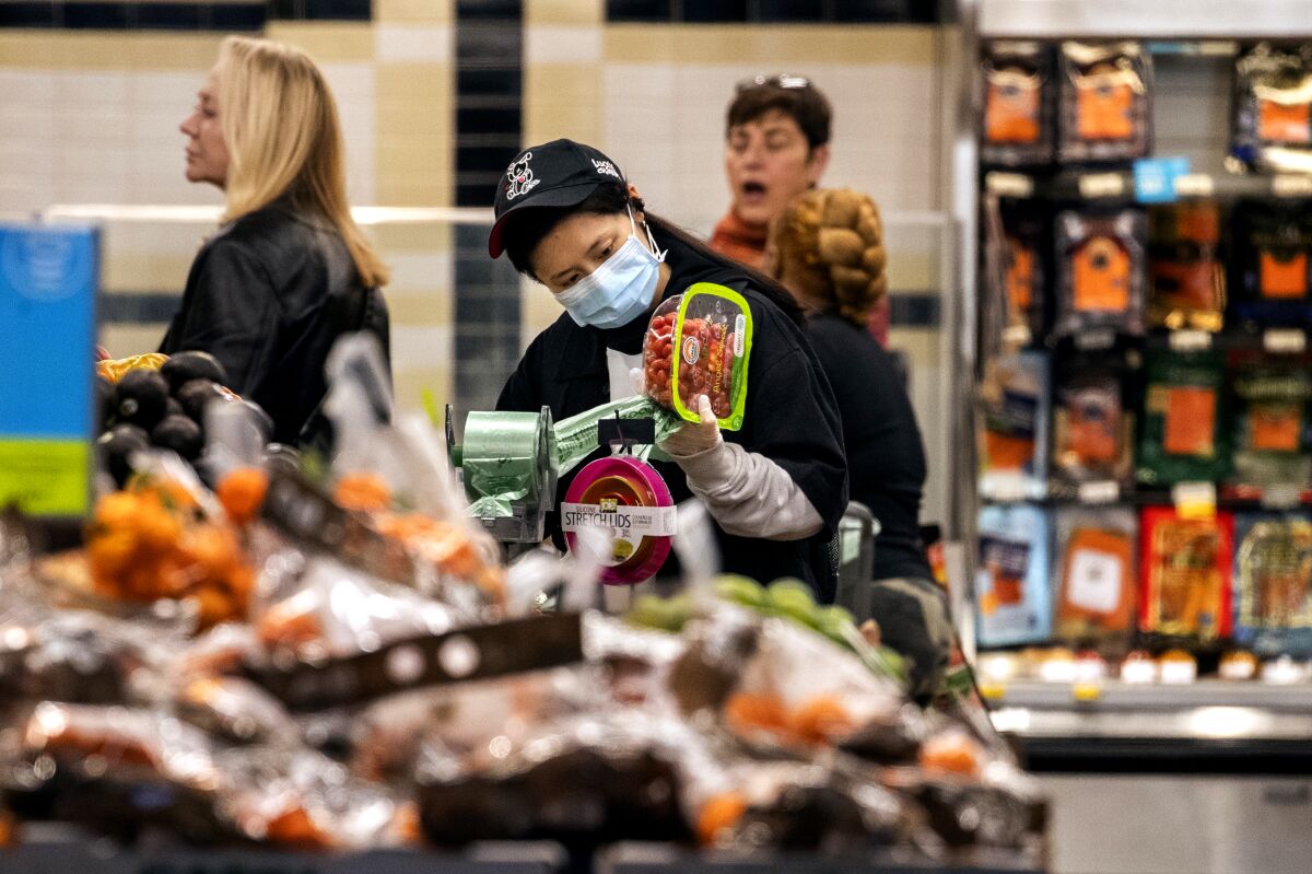 A shopper at a Whole Foods Market in Washington, D.C., checks a package of tomatoes.