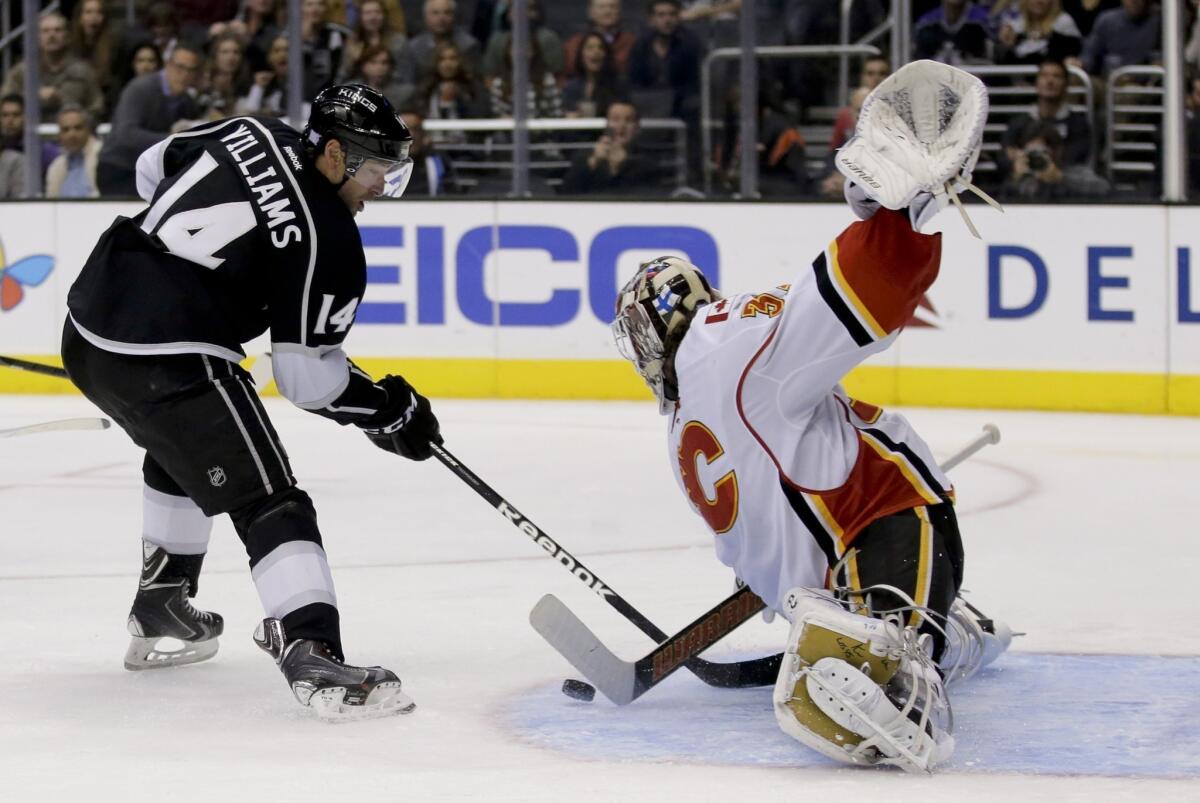 Calgary Flames goalie Karri Ramo, right, makes a save on Kings right wing Justin Williams during the first period of the Kings' 3-2 loss Monday.