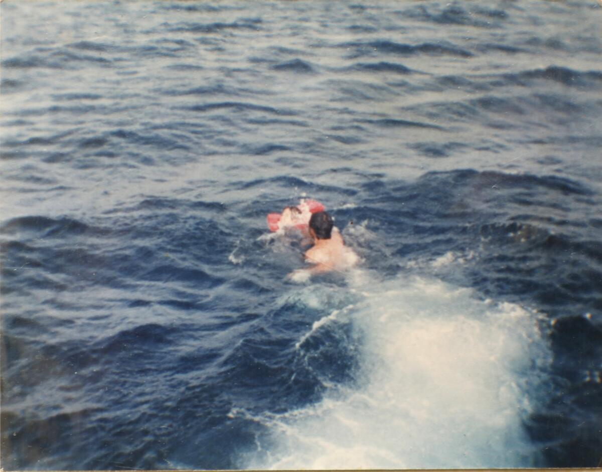 A man swims for a child in a life jacket