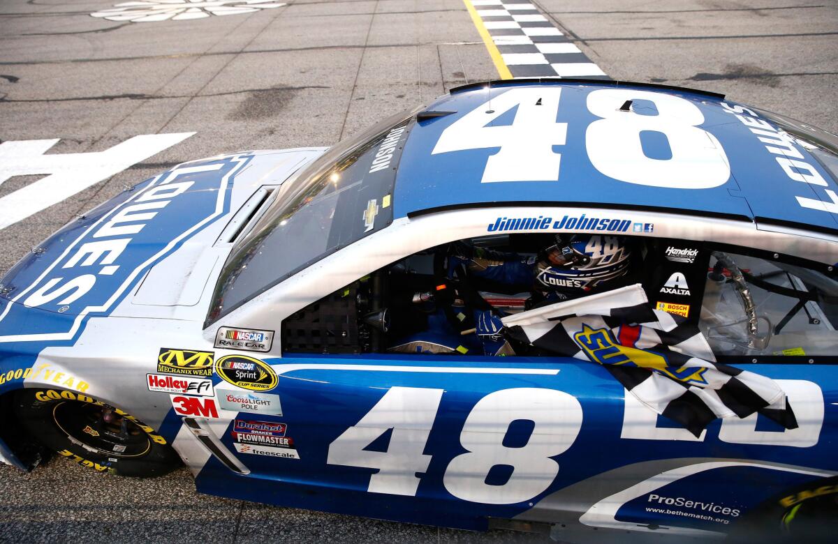 NASCAR driver Jimmie Johnson takes a victory lap with the checkered flag at Atlanta Motor Speedway on Sunday.