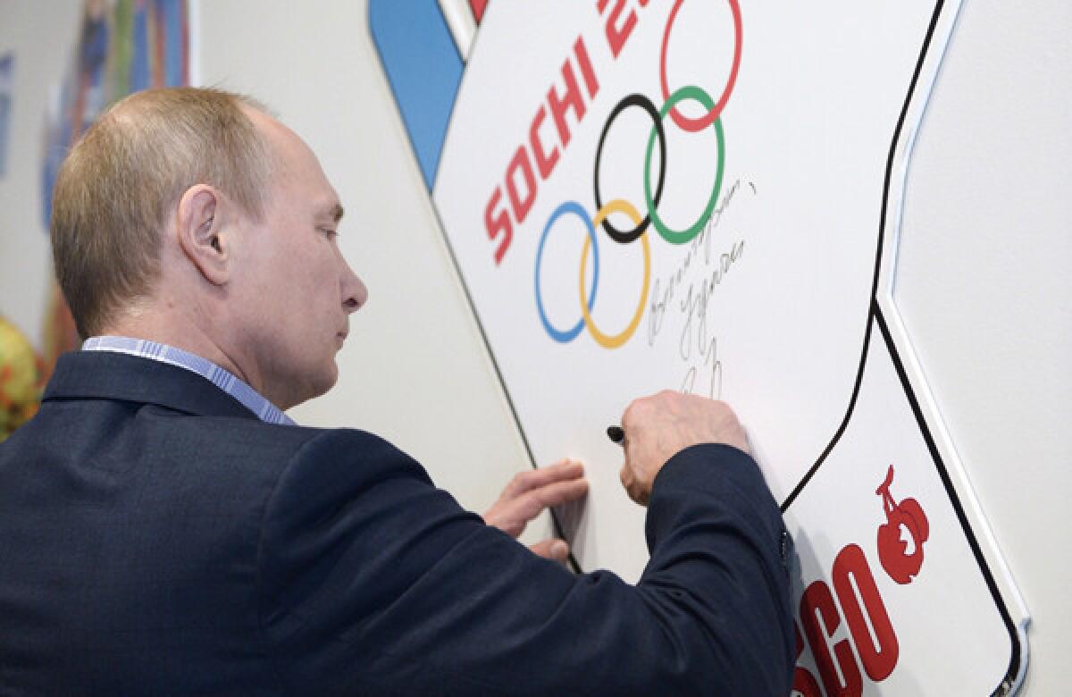 Russian President Vladimir Putin signs his name during a visit to a training center for Winter Olympic Games volunteers in Sochi, Russia, on Saturday. The Black Sea resort city will play host to the 2014 Olympic Games next month.