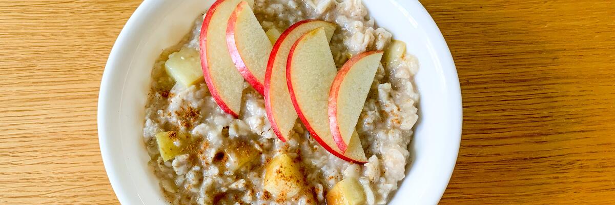 A bowl of oatmeal with apple slices on top