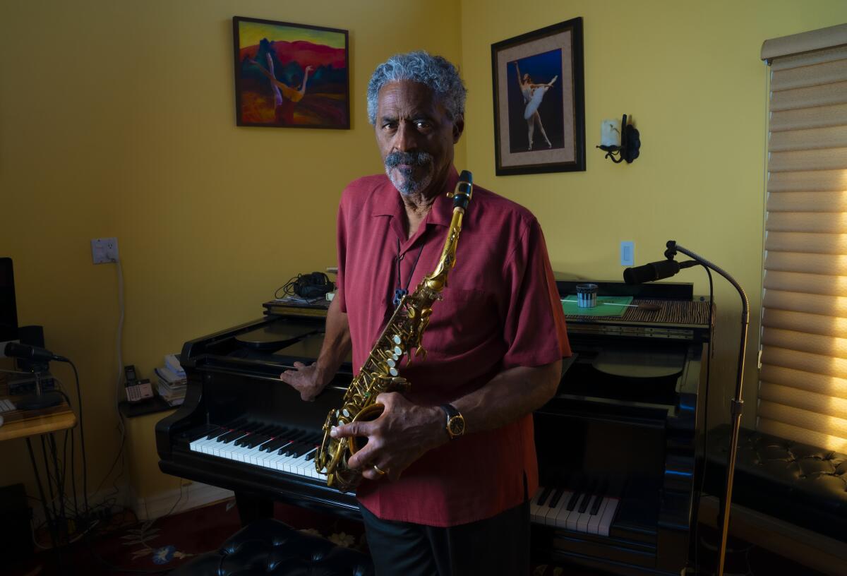 San Diego-based jazz sax great Charles McPherson, wearing a red shirt, holding a saxophone while leaning against a piano