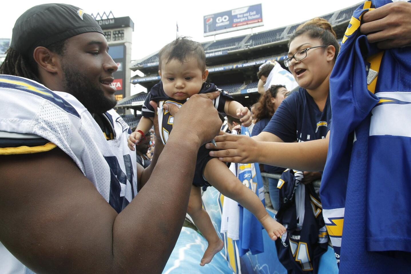 Chargers fan Cindy Huertas hands her 6-month-old son Marilyn Shay Dominguez to the Chargers' D.J. Johnson so that he could sign the baby's jersey during FanFest 2014 at Qualcomm Stadium on Saturday, August 2, 2014.