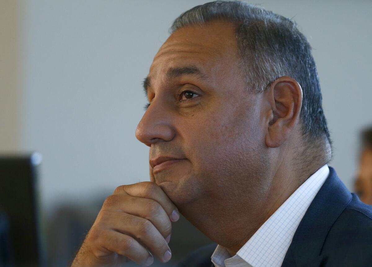 A closeup of Gil Cisneros facing left, his chin on his right hand