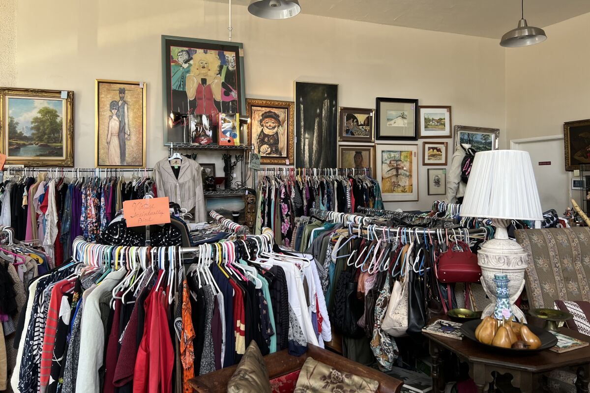 Clothing racks and paintings on display at AIDS Assistance thrift shop.