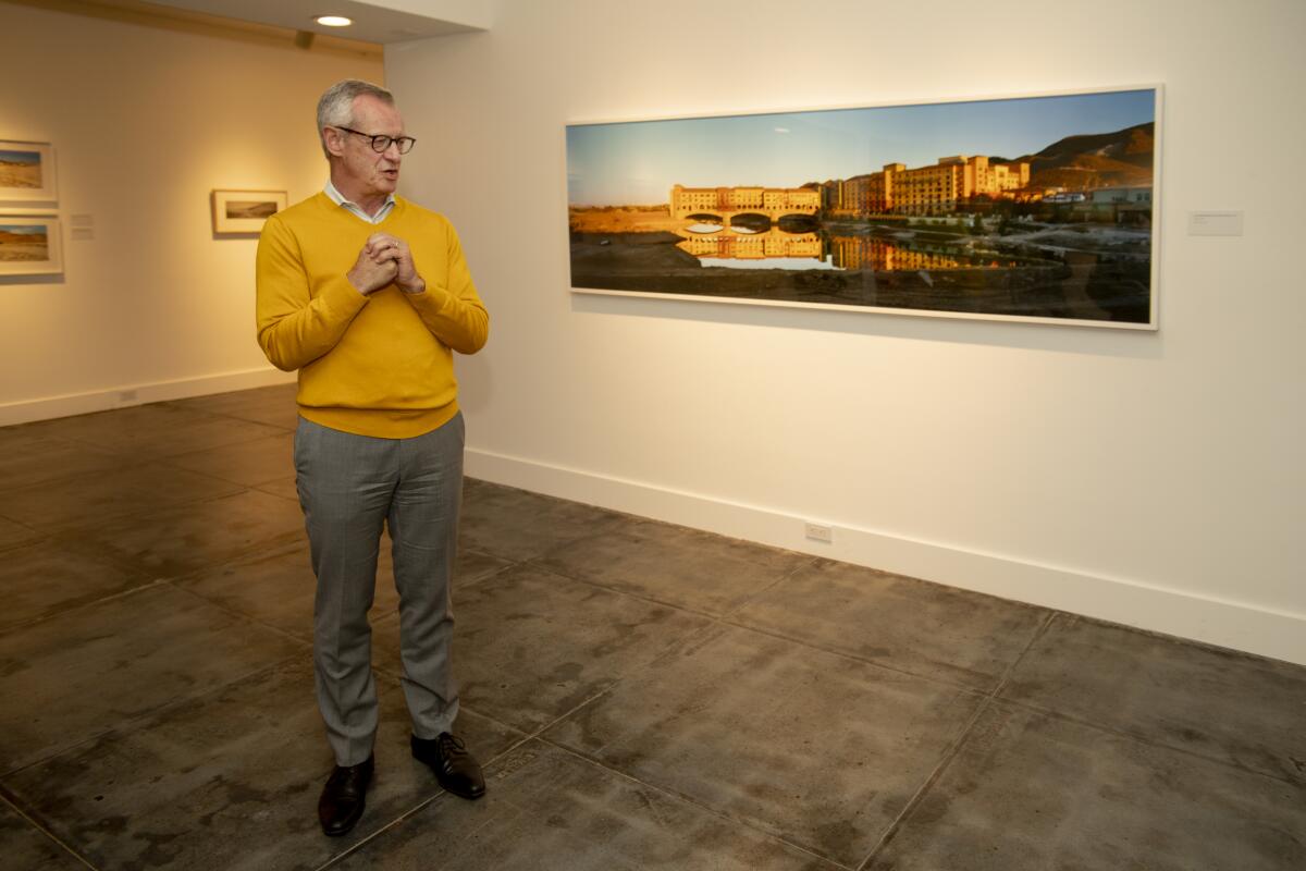 Laguna Art Museum Executive Director Malcolm Warner welcomes visitors Wednesday in front of a photograph by Newport Beach artist Laurie Brown.