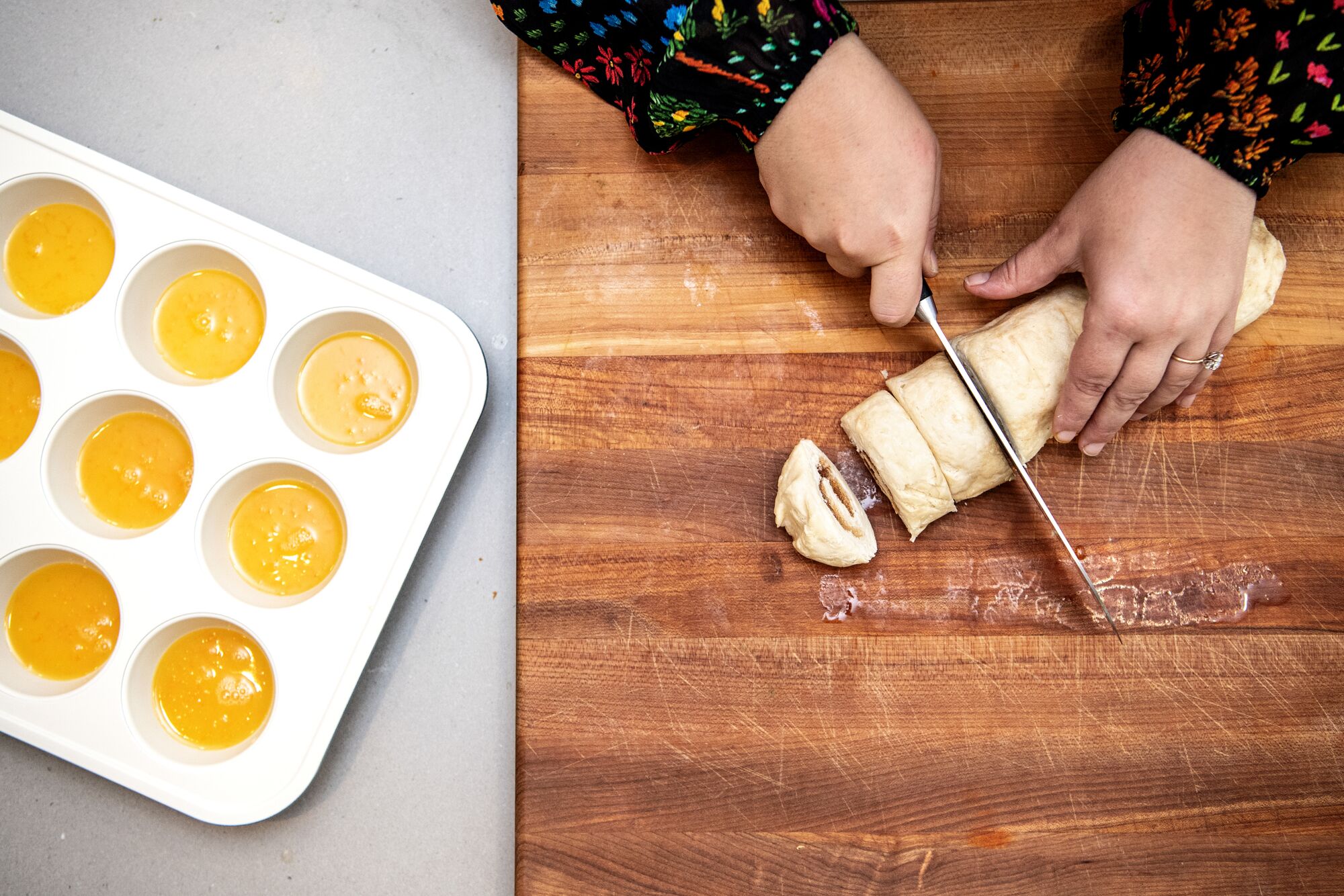 Overhead image of hands cutting rolled dough to make biscuits.