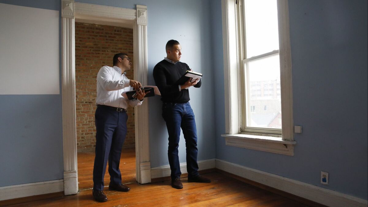 Gabriel Villagomez, right, works with real estate broker and consultant Miguel Chacon at a property in Chicago on June 12.