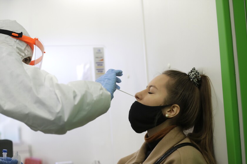 FILE- A woman undergoes the rapid antigen test for the coronavirus in Prague, Czech Republic, Wednesday, Dec. 16, 2020. On Wednesday Jan. 5, 2022 the Czech Republic's government decided to cut quarantine restrictions from fourteen to five days while also similarly shortened time for close contacts of infected people to isolate. (AP Photo/Petr David Josek, file)
