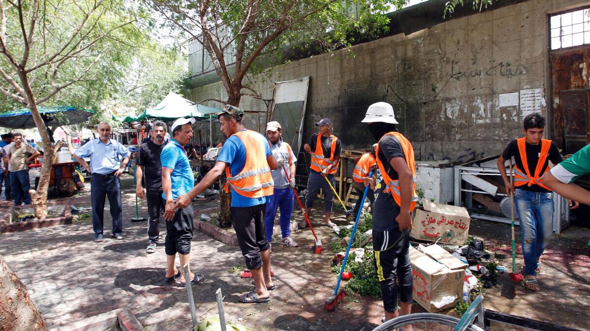 Iraqi workers clean the pavement at the site of a suicide bombing in the Kadhimiyah area, home to a major Shiite shrine.