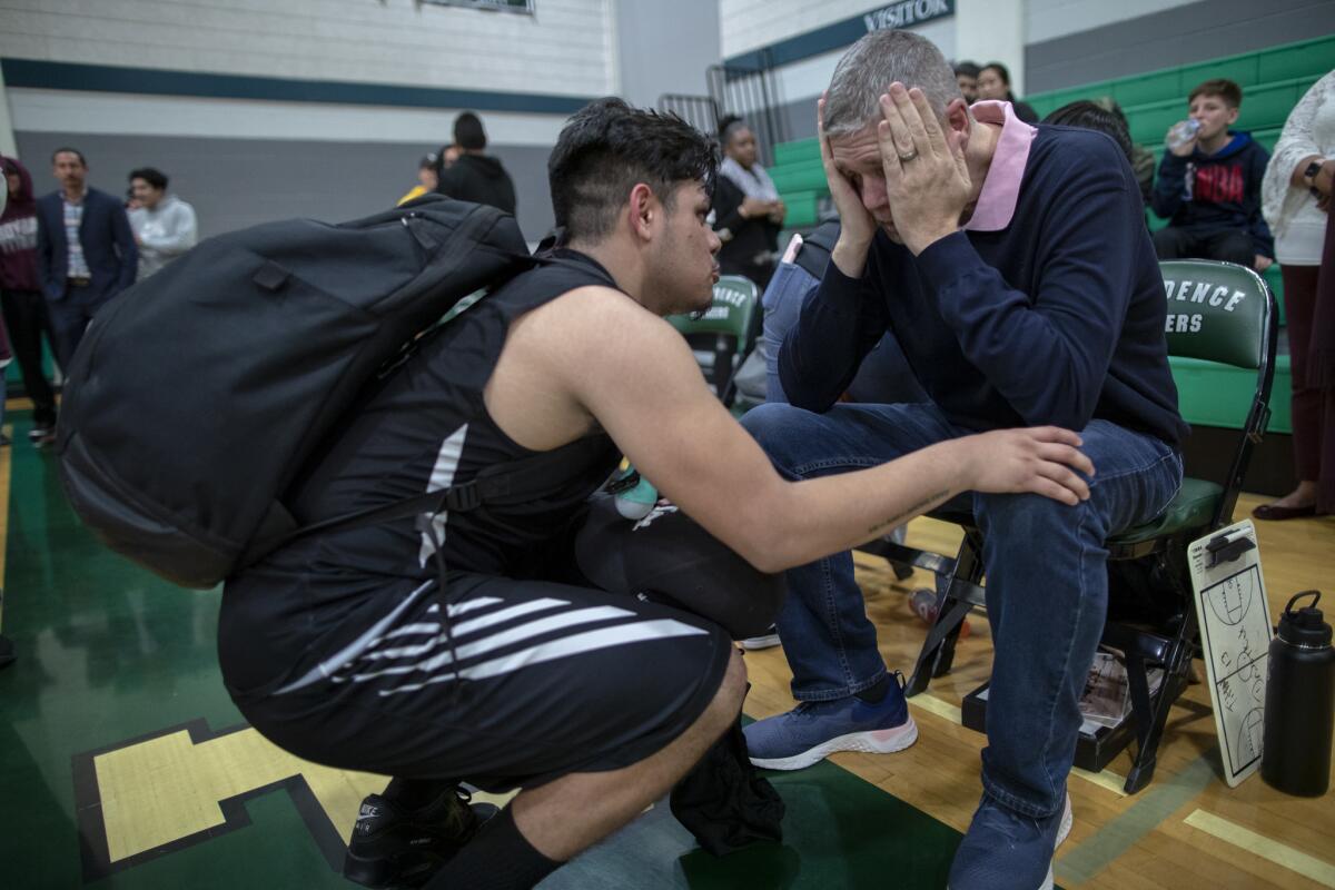 Isaac Torres comforts Roybal High School basketball coach Danny O'Fallon moments after losing 73-33 to Providence in the first round of the state playoffs last season.