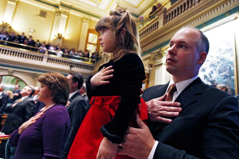 Rep. Kevin Priola, R-Henderson, holds his daughter Bremma, 5, during the singing of the National Anthem during the opening session of the Legislature at the Capitol in Denver on Wednesday, Jan. 12, 2011.(AP Photo/Ed Andrieski)