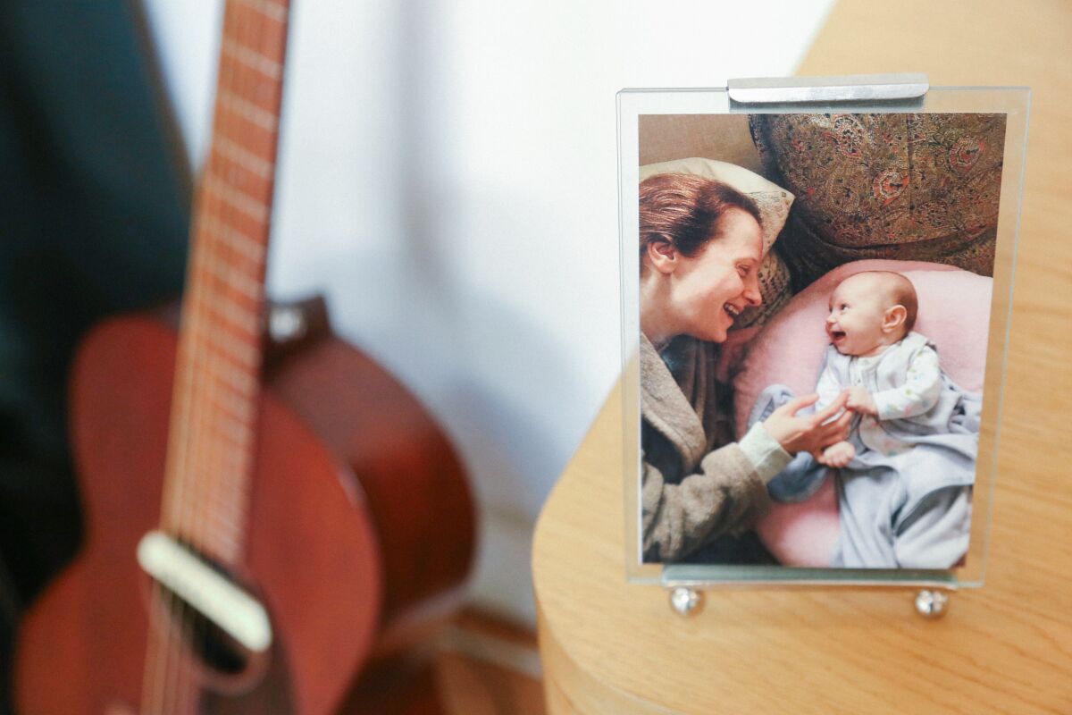 A guitar next to a photo of a woman and a baby. 