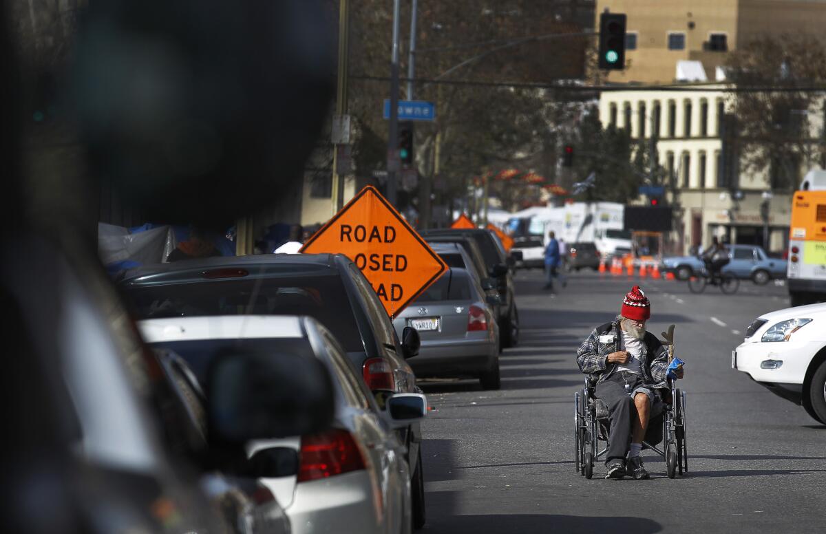 A man who said he was a Navy veteran pushes his wheelchair backward on skid row.