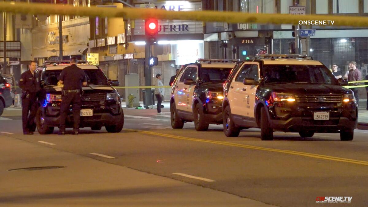 Several law enforcement vehicles are parked on a street at night in front of yellow police tape.