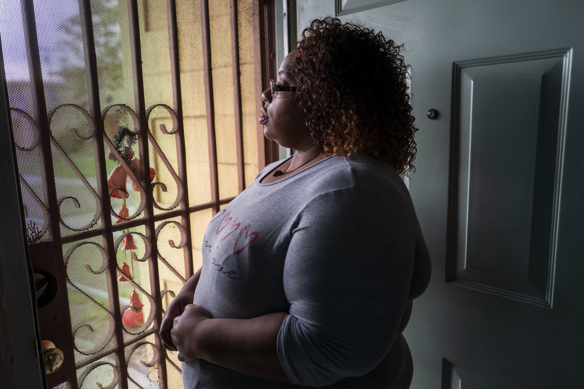 A woman looks out her front door.