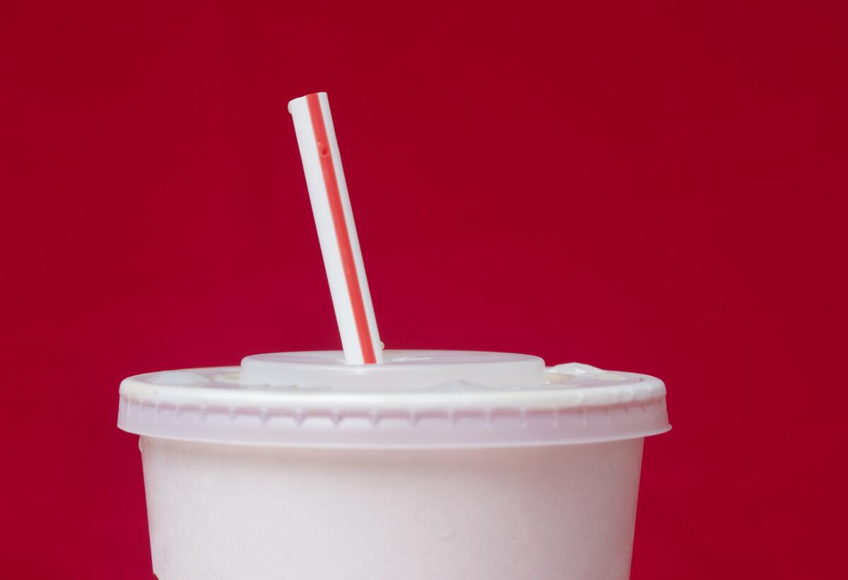 A large soft drink with a plastic straw from a McDonald's restaurant.