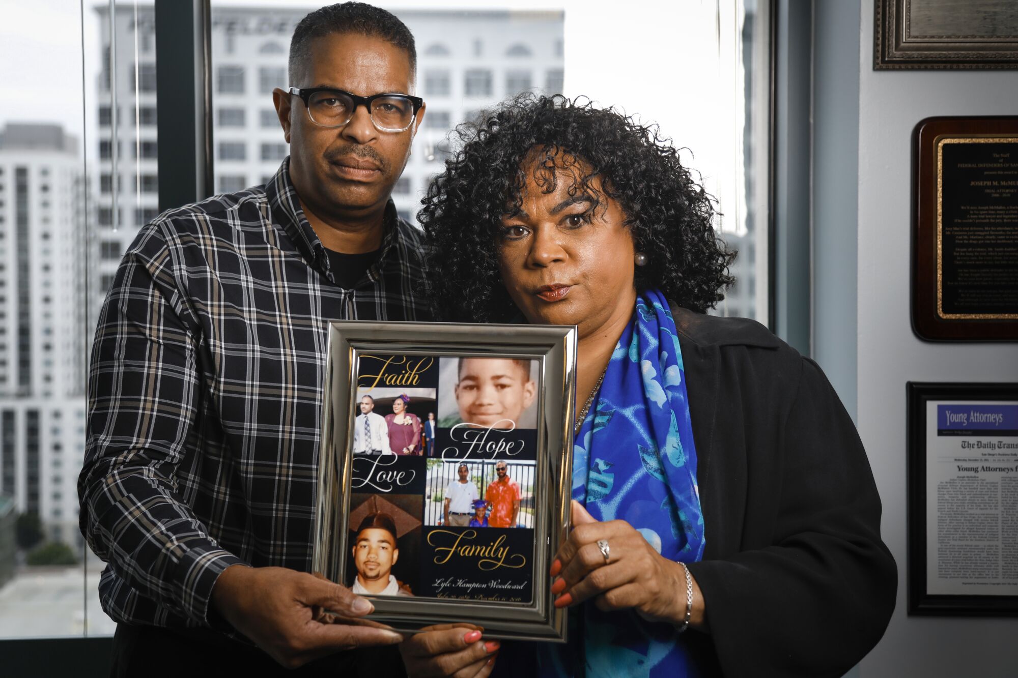 Edward Woodward, left, and his ex-wife, Bessie Woodward, right, hold a framed photo collage of their son, Lyle Woodward, June 26, 2019 in San Diego, California, who died while in San Diego County Jail.