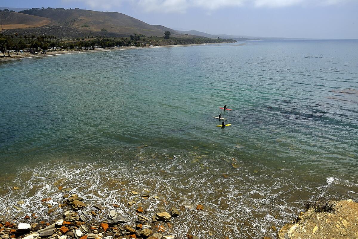 Refugio State Beach overlooking the ocean with three kayakers in it.