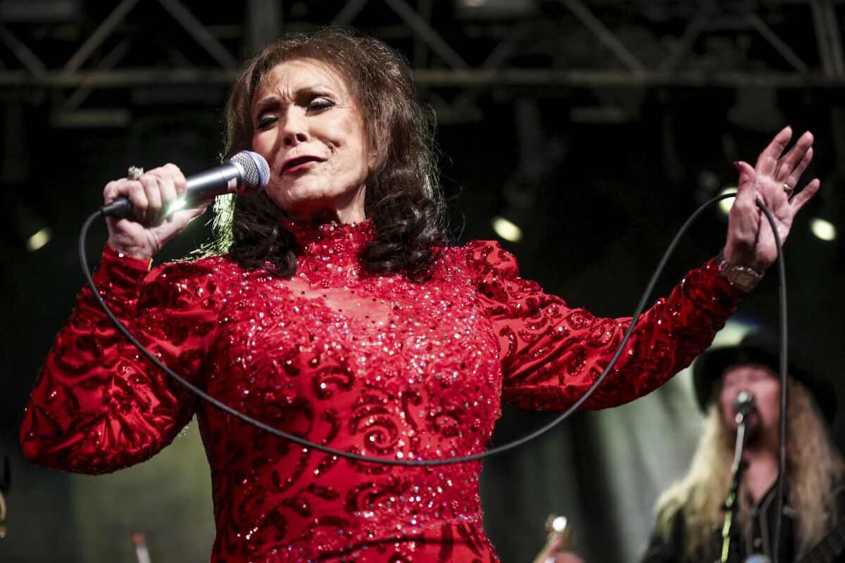 A woman in a red dress sings into a microphone