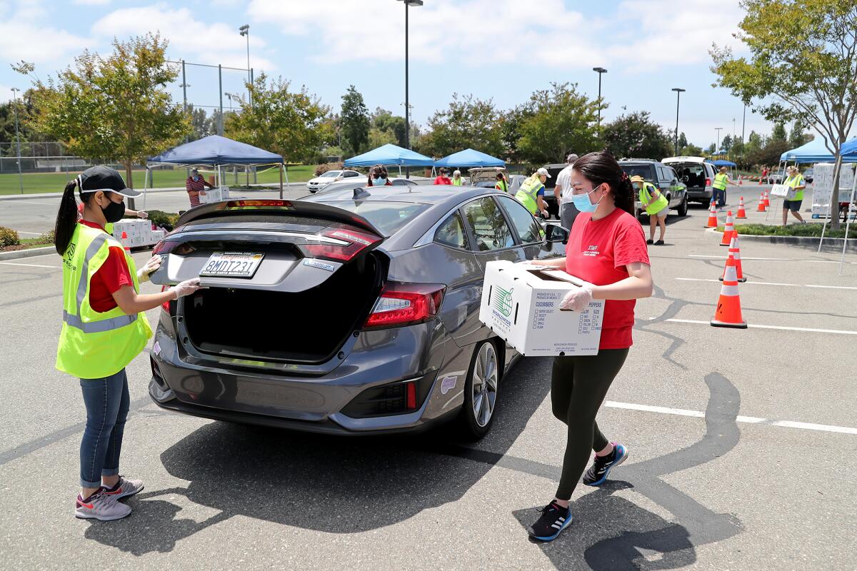 Volunteers help load Worldwide Produce pre-boxed groceries for 1,000 families during a drive-through food giveaway on Friday.