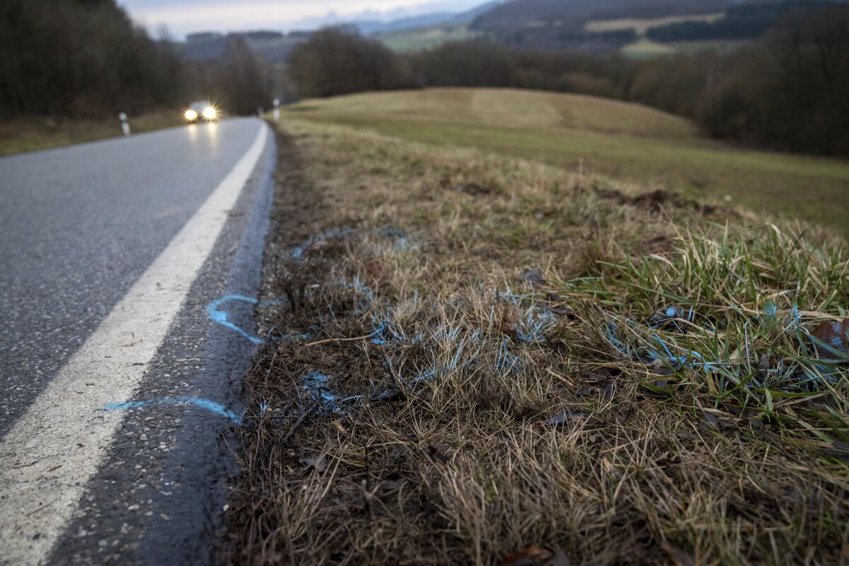 Markings were applied on the edge of county road 22 between the towns of Mayweilerhof and Ulmet in Germany, Tuesday, Feb.1, 2022. The day before, a policewoman and a policeman were shot there during a traffic control. (Harald Tittel/dpa via AP)